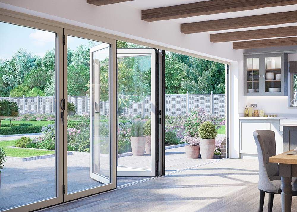 interior image of white aluminium bifold doors opening to a bright garden