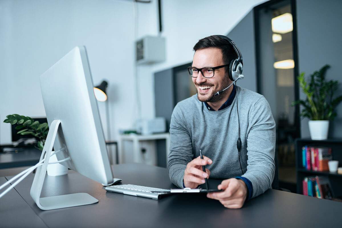 customer service male smiling whilst talking on a headset